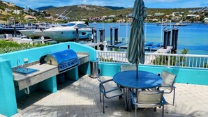 Une terrasse extérieure équipée d’un barbecue, de sièges et offrant une vue sur la marina et sur l’eau.