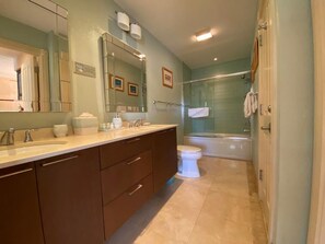 Ein modernes Badezimmer mit großem Spiegel, zwei Waschbecken, Toilette und einer Duschkabine.