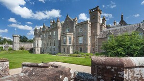 A historic stone building with a large lawn in front.