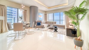 A spacious living room with a modern design, featuring a large sofa, a dining area, and a large window with a city view. - Sophisticated 2BR at DAMAC Towers by Paramount A Business Bay by Deluxe Holiday Homes (Dubai)