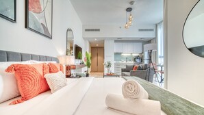 A modern hotel room with a neatly made bed, a dining area, and a kitchenette. - Picturesque Studio at Mesk 1 Midtown Dubai Production City by Deluxe Holiday Homes (Dubai)