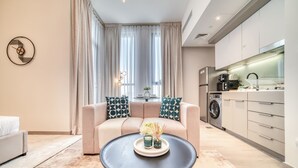Una sala de estar moderna con un sofá, una mesa de centro y una zona de cocina con electrodomésticos.