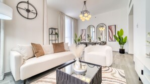 A modern living room with a sofa, coffee table, and decorative mirrors. - Harmonious 2BR w/ Assistant’s Room at Mesk 1 Midtown Dubai Production City by Deluxe Holiday Homes (Dubai)