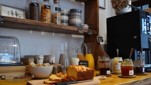 Un comptoir de boulangerie avec une miche de pain, des pots de confitures et une machine à café.