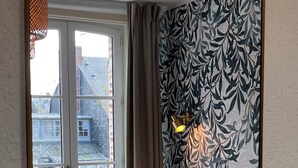 Une chambre à coucher avec un lit, une fenêtre, un mur à motifs et un luminaire.