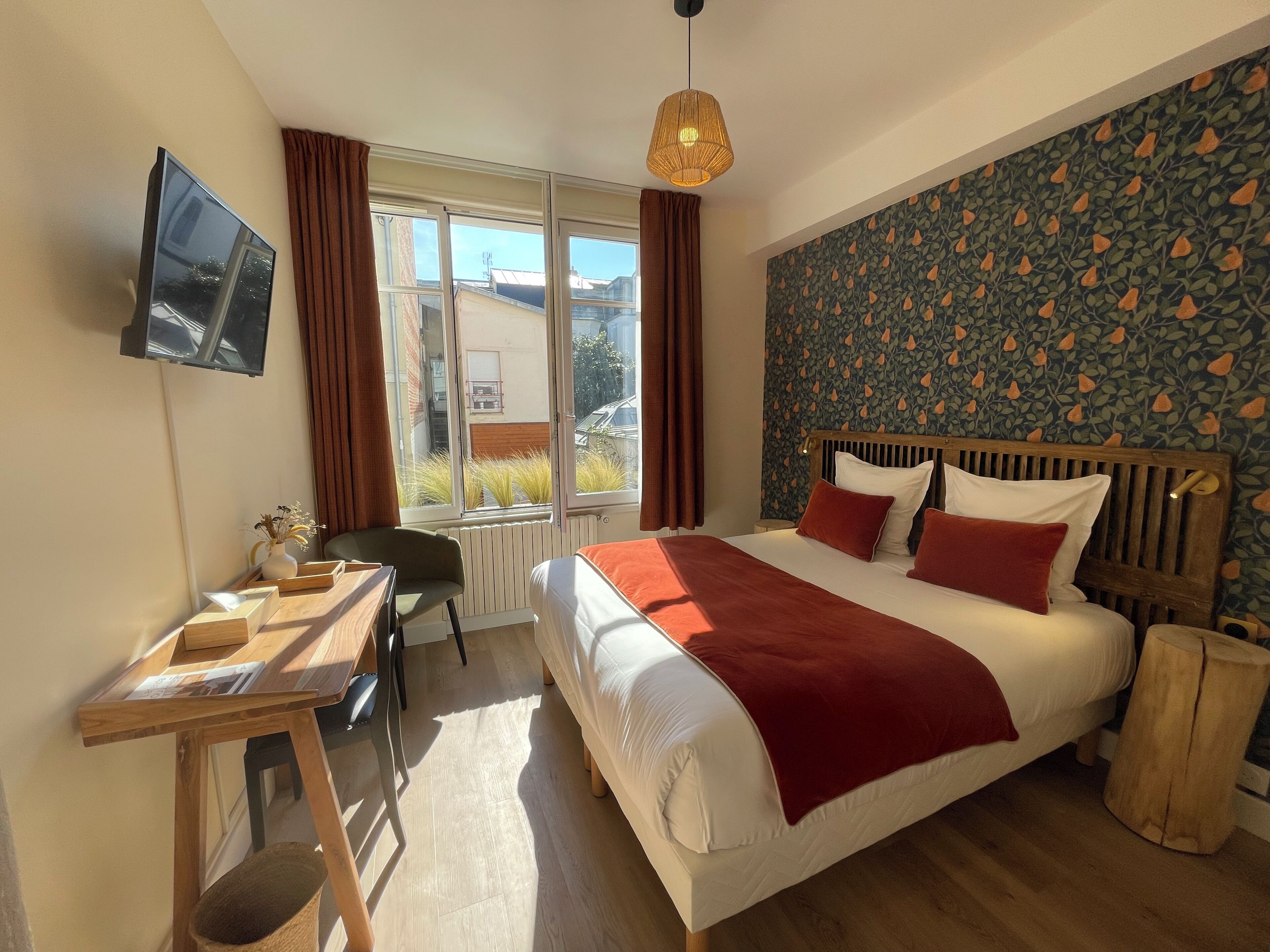 Une chambre à coucher comprenant un lit, un bureau, une chaise, un téléviseur et une fenêtre avec des rideaux.
