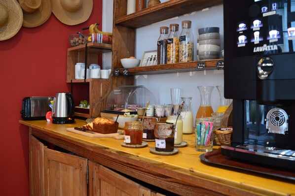 A kitchen counter with a coffee machine, jars of condiments, and a loaf of bread.