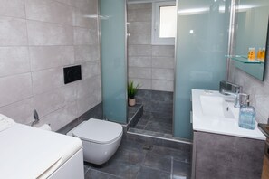 A modern bathroom with a toilet, sink, and shower area.