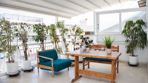 A bright room with a wooden table and blue chairs, surrounded by potted plants. - Spacious 2 level Brand New apt GTD3194 (Athens)