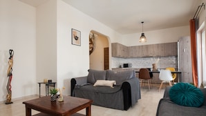 A modern living room with a sofa set, a coffee table, and a kitchen in the background. - Spacious 2 level Brand New apt GTD3194 (Athens)