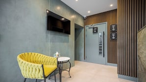 Un moderno vestíbulo de hotel con una silla amarilla, una mesita y señalización para las habitaciones G1 a G6.