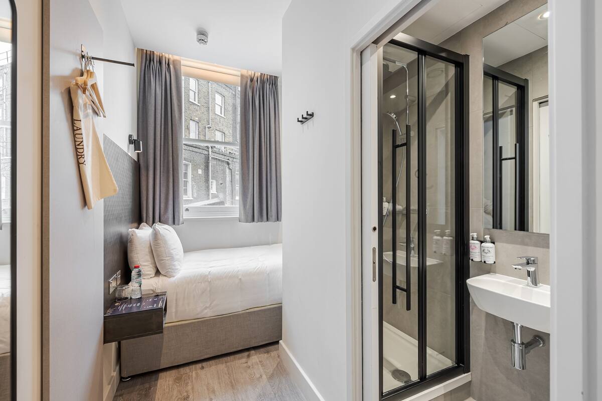 A modern bedroom with a bed, bedside table, and a window with curtains.
