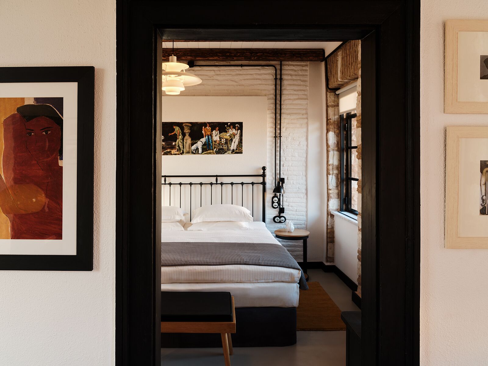 A bedroom with a bed, a nightstand, a lamp, and a painting on the wall.