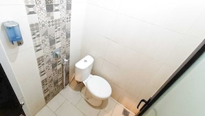 A small bathroom with a toilet, a hand dryer, and a patterned tile wall. - Casa TS 16 Guest House by Pesen Kamar (Malang)