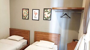 A hotel room with two wooden beds, a shower area, and three framed pictures on the wall. - Casa TS 16 Guest House by Pesen Kamar (Malang)