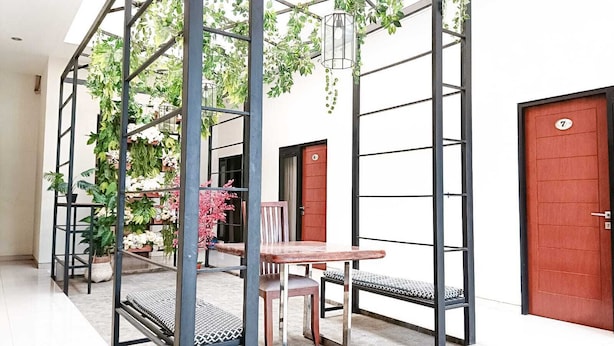 A modern interior with a metal partition, a wooden table, and chairs. There are potted plants and a door with a number. - Casa TS 16 Guest House by Pesen Kamar (Malang)