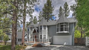 Ett tvåvåningshus med en veranda som löper runt hela huset, stora fönster och ett garage.