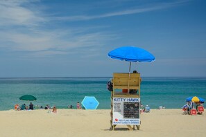 A beach scene with a lifeguard station named 'Kitty Hawk' and a blue umbrella.