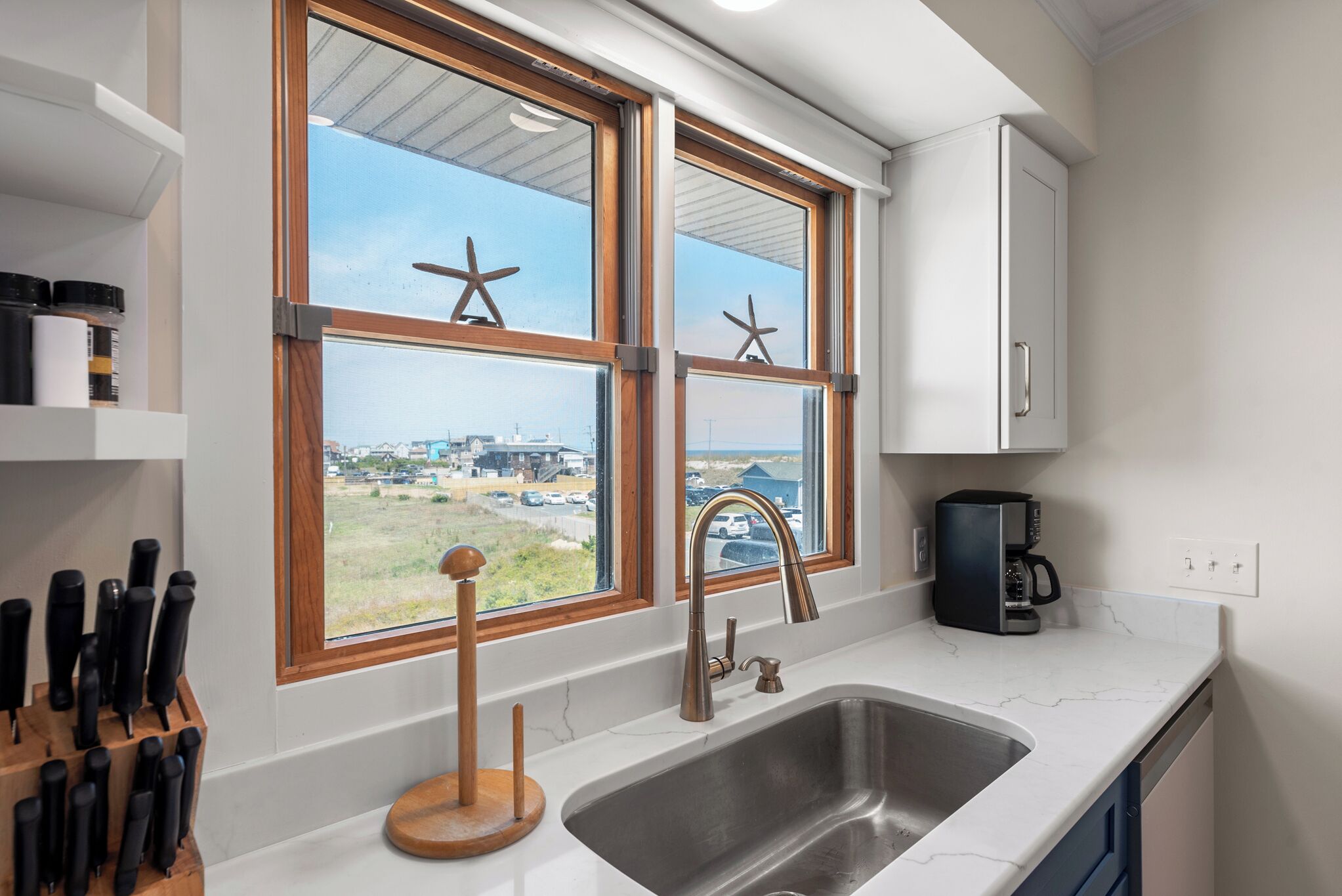 A kitchen with a large window, a sink, and a coffee maker.