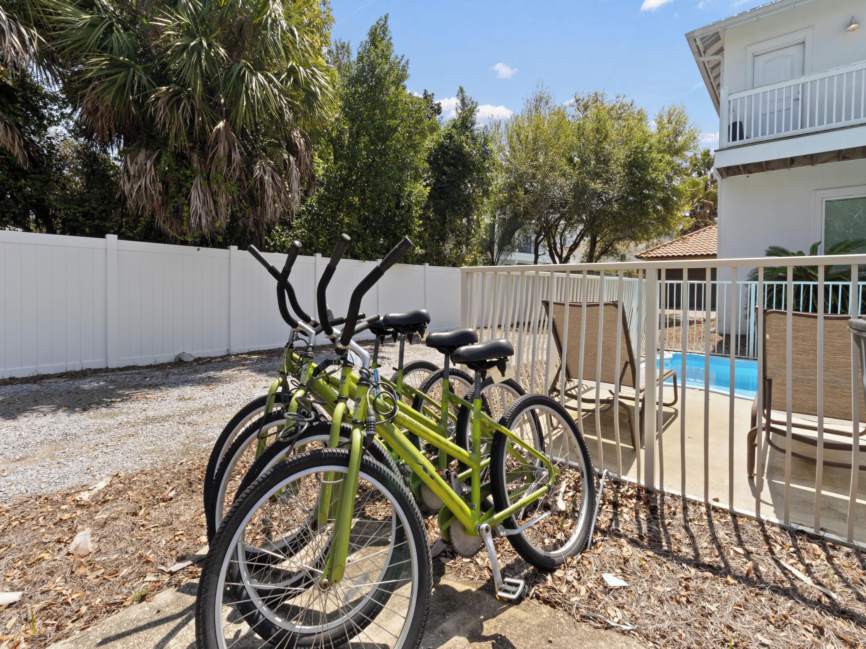 A gated outdoor area with bicycles parked near a pool and a white fence.