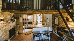 A rustic interior with a stone wall, wooden bar, and a staircase. - Romantic stay with spa, sauna and home cinema (Beaumontois-en-Périgord)