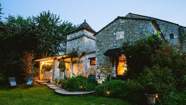 A stone building with a covered outdoor seating area and a well-maintained garden. - Romantic stay with spa, sauna and home cinema (Beaumontois-en-Périgord)