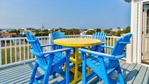 Una terraza con una mesa amarilla y sillas azules, con vistas a una zona residencial.
