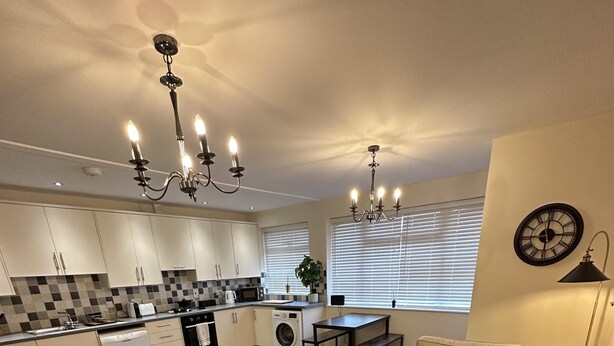 A modern living room with a sofa, armchair, coffee table, and a dining area with a table and chairs. - Charming 2-bed Apartment in Danbury, Essex (Chelmsford)