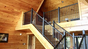 Un escalier en bois avec des rampes en métal menant à un deuxième étage.