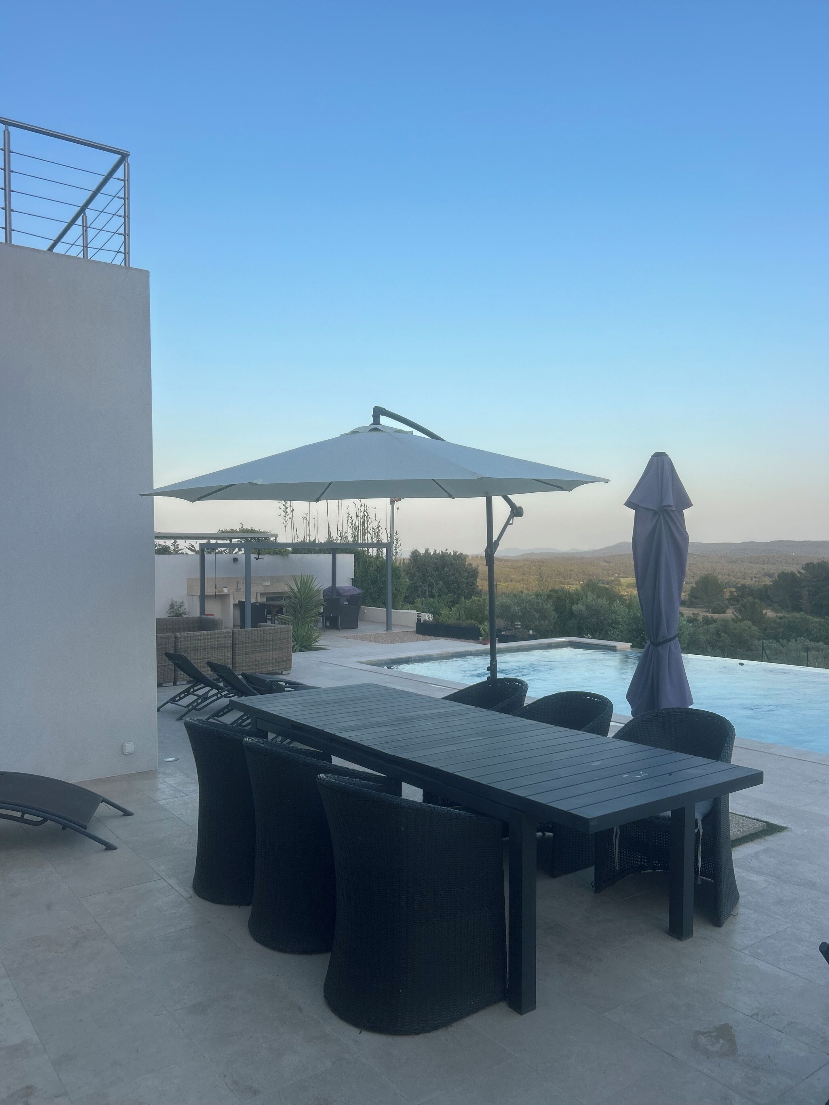 Eine Dachterrasse mit Pool, Gartenmöbeln und freiem Blick auf die Landschaft.