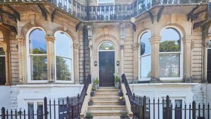 A grand entrance with a staircase, arched windows, and a black iron railing. - Host & Stay | Brooklands Timeless (Scarborough)