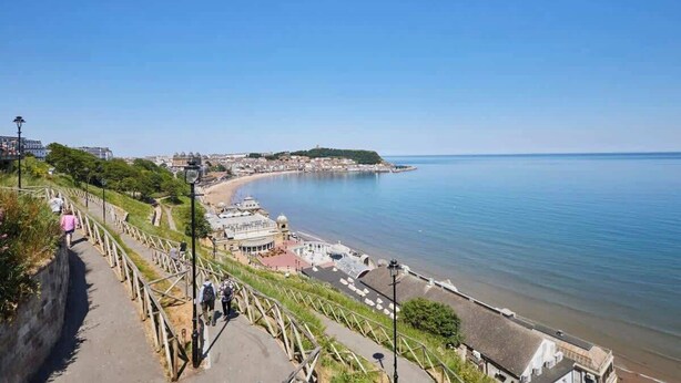 A coastal town with a promenade overlooking the sea, a historic building, and a clear blue sky. - Host & Stay | Brooklands Timeless (Scarborough)