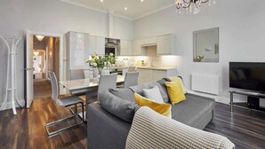 A modern living room with a grey sofa, a dining area, and a kitchen. - Host & Stay | Brooklands Timeless (Scarborough)