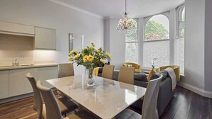 A modern kitchen with a dining area, featuring a large table, chairs, and a vase of flowers. - Host & Stay | Brooklands Timeless (Scarborough)