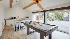 Una cocina moderna con mesa de billar, taburetes de bar y zona de comedor.