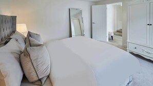 Un dormitorio con una cama grande, un espejo, un armario y una puerta que da a una escalera.