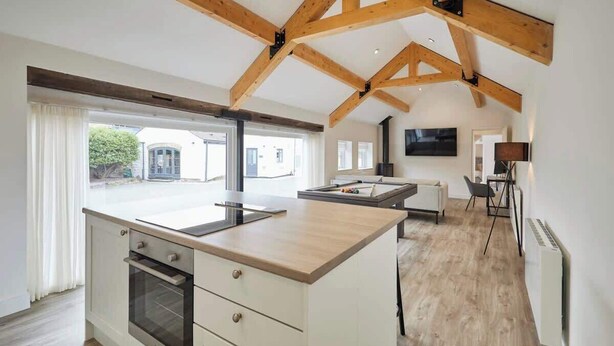 Una cocina espaciosa con una isla grande, vigas de madera y vistas al exterior.