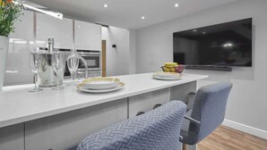 A modern kitchen with a white countertop, stainless steel appliances, and a large window. - Host & Stay | The Old Jail Barber's Shop (Scarborough)