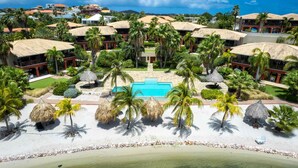 A resort with multiple buildings, a central pool, and palm trees. - Spanish Water Apartments - Premium Duplex (Sint Willibrordus)