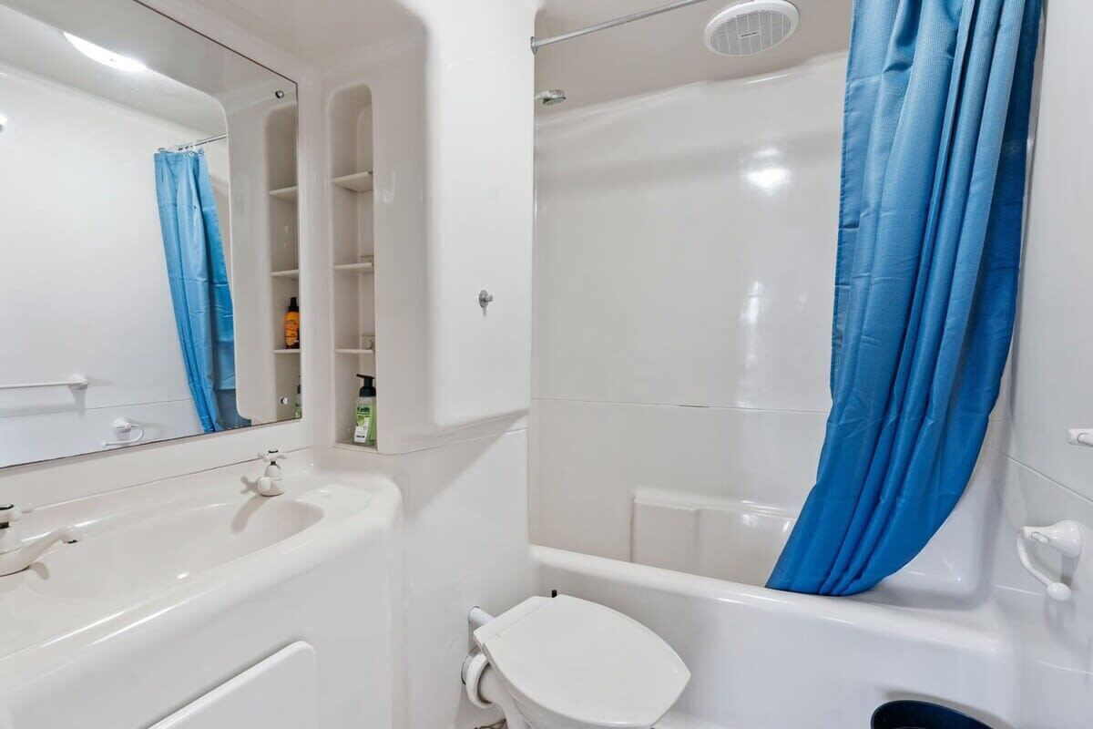 A bathroom with a white sink, toilet, and bathtub, a blue shower curtain, and a mirror.