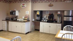 Un espace dédié au petit-déjeuner, équipé d’un four à micro-ondes, d’une machine à café et d’un panneau indiquant « Buffet du petit-déjeuner ».