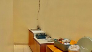 A small kitchen with a window, a sink, and a countertop with various kitchen items. - Kaja Guest House by Pesen Kamar (Malang)