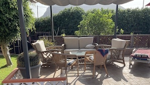 Un espace extérieur aménagé en terrasse, avec des meubles en osier, un canapé confortable et une petite table.