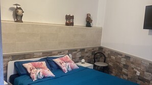 Une chambre à coucher comprenant un lit, une table de chevet, un téléviseur fixé au mur et des objets décoratifs.