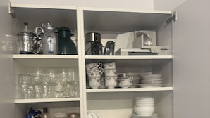 Une cuisine équipée d’un évier, d’un plan de travail et d’un placard contenant divers ustensiles et accessoires de cuisine.