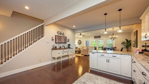 A spacious kitchen with white cabinets, a marble countertop, and a wooden staircase. - Cozy Deep Creek Cabin w/ Hot Tub & Fireplace (Oakland)