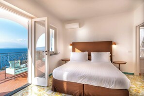 Une chambre avec un grand lit, un balcon avec vue et une porte donnant sur le balcon.