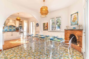 A spacious kitchen with a dining area, clear chairs, and a patterned floor.