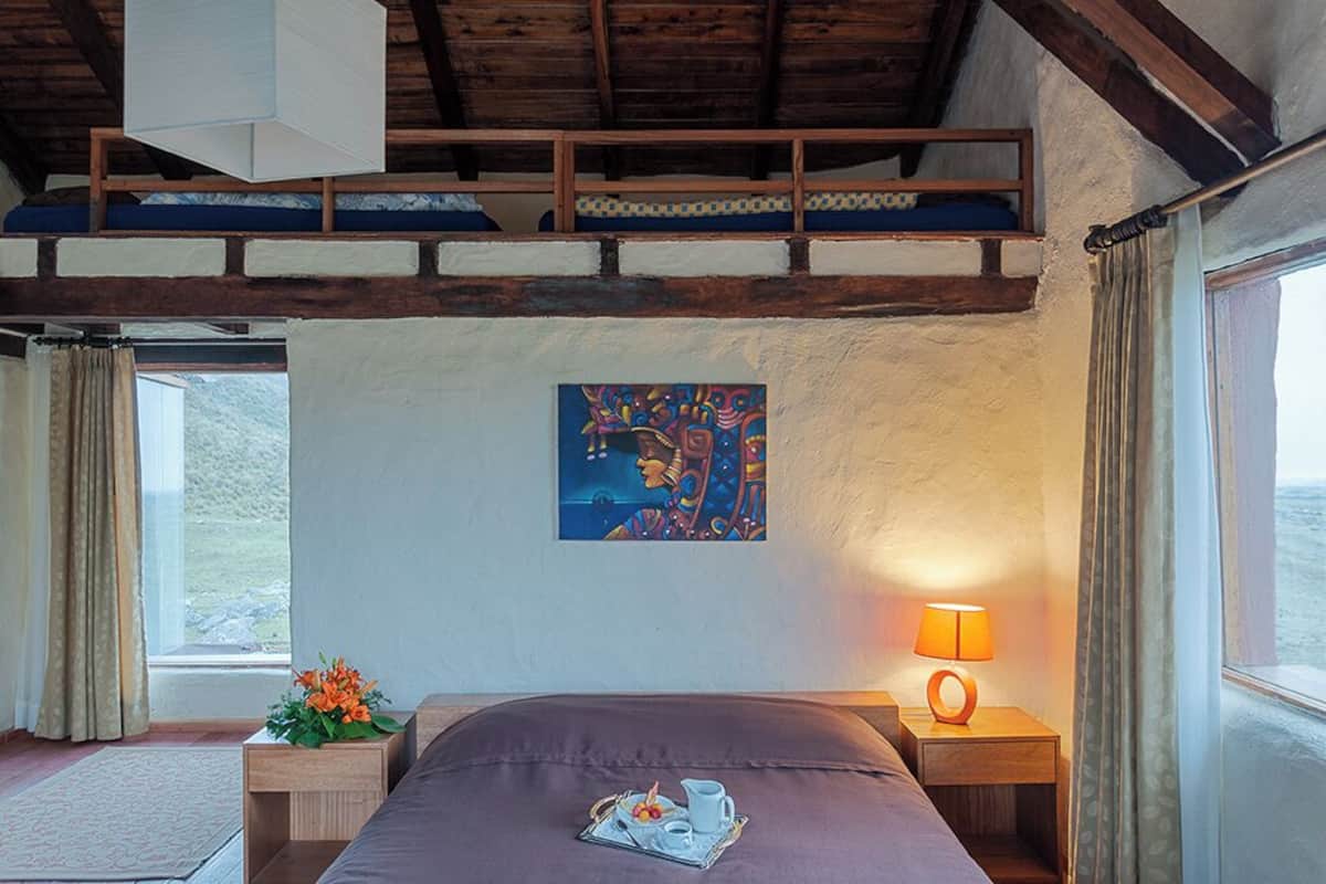 Ein Schlafzimmer mit einem Bett, einem Gemälde, einer Lampe und Blick ins Freie.