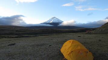 A tent in a grassy field with a mountain in the background.